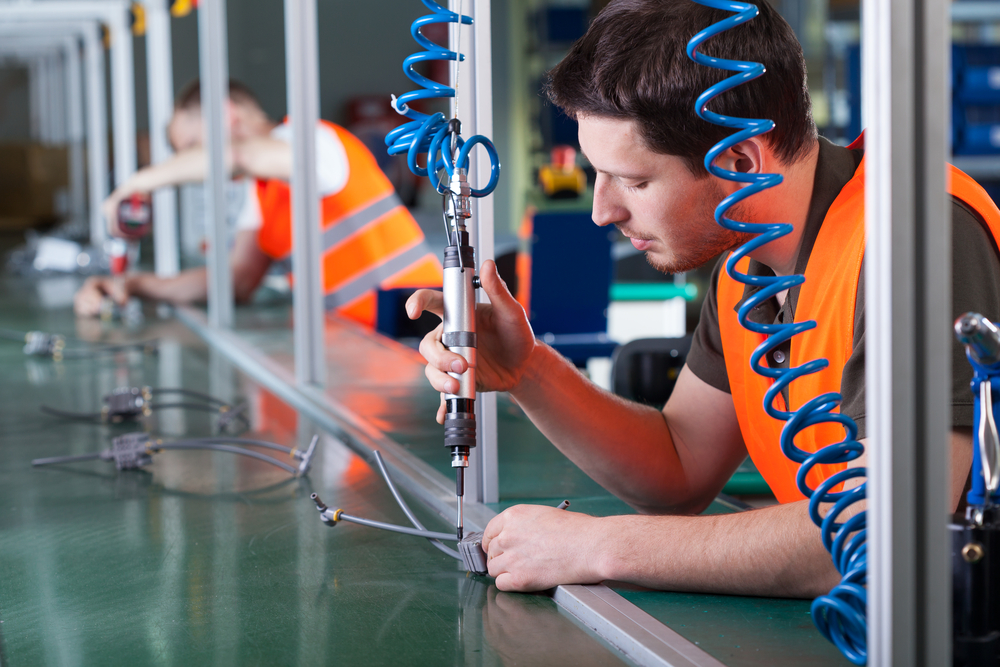 Men during precision work on production line, horizontal